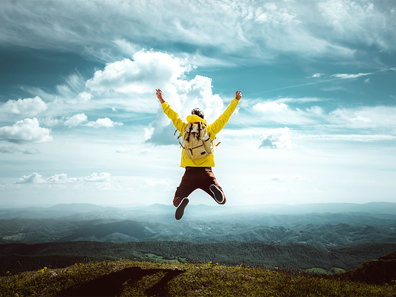 Man traveler on mountain summit enjoying nature view with hands